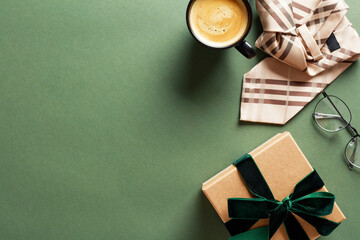 Top view photo of gift box, glasses, tie, coffee cup on dark green table. Happy Fathers Day card...