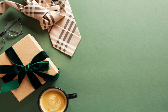 Happy Fathers Day card design. Top view gift box with green ribbon bow, glasses, tie, coffee cup on dark green background