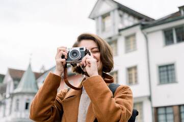 Happy woman taking a photo with an analog camera outdoors