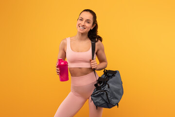 A cheerful young woman dressed in a pink sports bra and leggings stands confidently against a vivid...