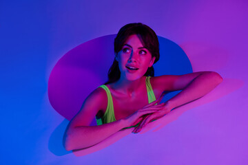 Photo of amazed girl in round hole lean placard look empty space isolated vivid neon background