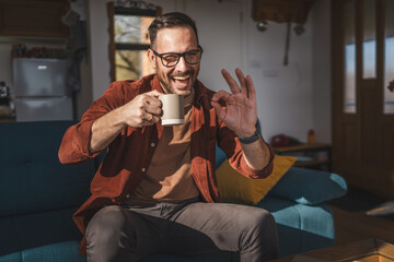 One adult caucasian man sit at home and hold cup of coffee enjoy home
