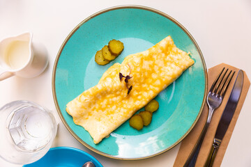 Thin omelette served with pickled cucumber slices garnished with microgreen served for breakfast..