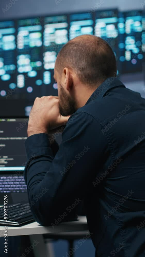 Poster vertical video man in server room typing code on laptop and pc, ensuring data remains shielded from 