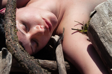 portrait of a sensual, seductive sexy young woman enjoying forest bathing lying between branches