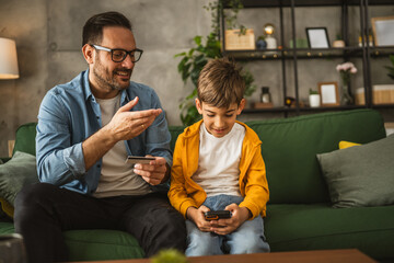 Father and son buy online with credit card on mobile phone at home