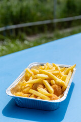 Aluminium tray filled with deep fried food in a street food kiosk: french fries, Olive all'Ascolana, typical Italian meat filled olives, and mozzarella fried balls. Unhealthy fried food.