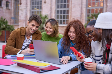 Group of happy multiracial students meeting to study together at university campus using laptop and...