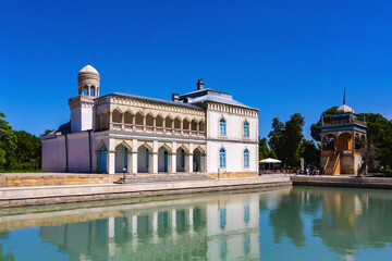 Emir's Summer Palace in Bukhara, elegant structure mirrored in a reflective pond, set against a vivid blue sky. Bukhara, Uzbekistan - obrazy, fototapety, plakaty