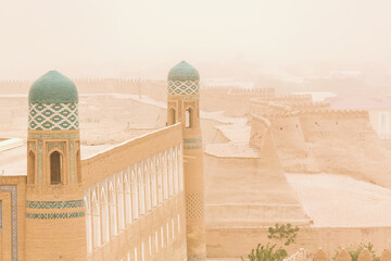 Khiva ancient city walls and turquoise-tiled minarets shrouded in a sandstorm, timeless and...