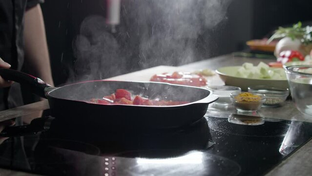 Cook adds juicy red bell peppers, sliced into small pieces, to the vegetables. This causes oil to splatter out of the frying pan onto the electronic stove, staining everything in the kitchen. Medium