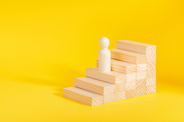 Businessman climbing stairs. Business growth success process, career ladder. Ambitions concept. Wooden figurine on yellow background