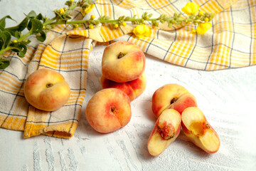 Halves and several whole saturn peaches or flat peach on white wooden background..