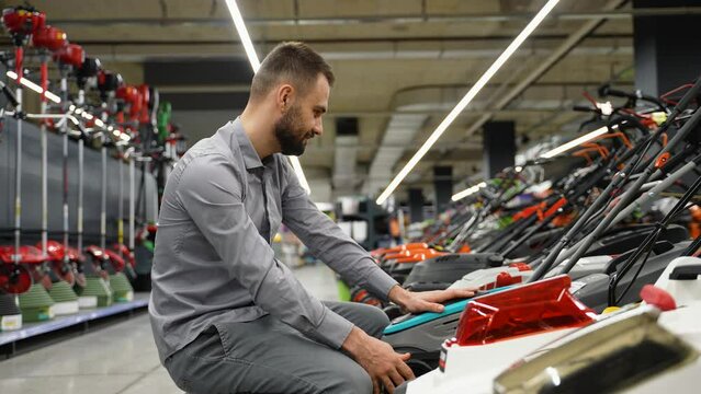 A man in garden store choosing lawnmower