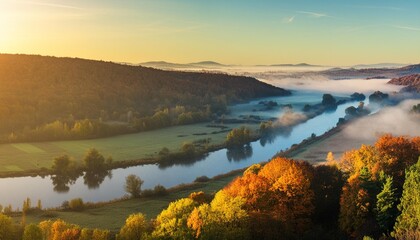 amazing panoramic view of blue foggy river and colorful forest on sunrise autumn landscape