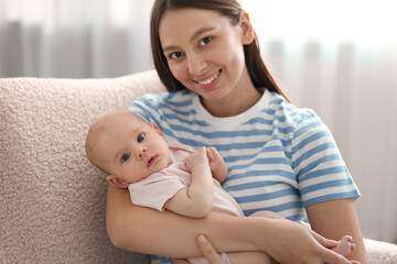 Mother with her cute baby in armchair at home