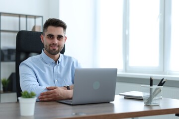 Happy young programmer working with laptop in office