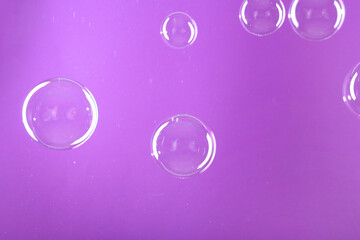 Beautiful transparent soap bubbles on violet background