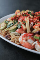 Instant noodles spicy salad with shrimp and vegetable on black table. Yum Mama Thai cuisine Yum traditional spicy hot