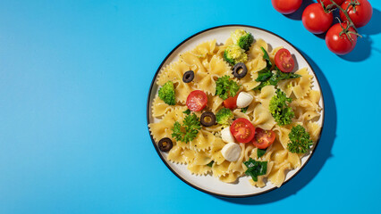 Delicious pasta salad with farfalle, cherry tomatoes, olives, mozzarella, broccoli, and parsley on a blue background.