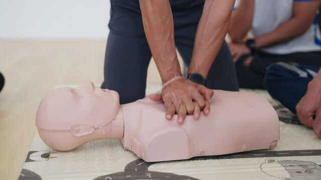 A man is performing CPR on a mannequin. The scene is instructional and educational, as it teaches people how to perform CPR in case of an emergency