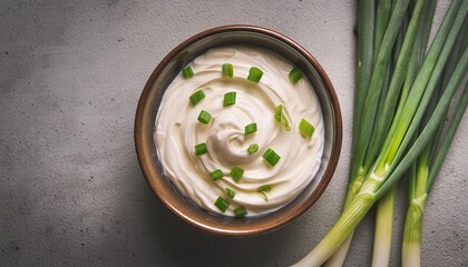 top view of sour cream or mascarpone cheese in ceramic bowl with scallions creamy texture copy space gray concrete background