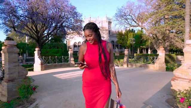 Mujer alegre con el tel&eacute;fono m&oacute;vil haciendo turismo de compras en una ciudad europea.