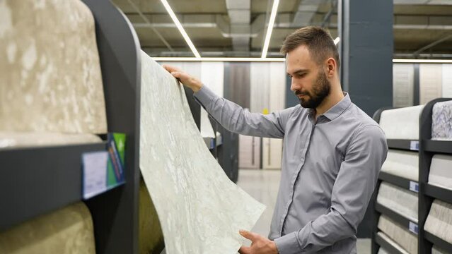 A man looking samples of designer wallpaper in household store