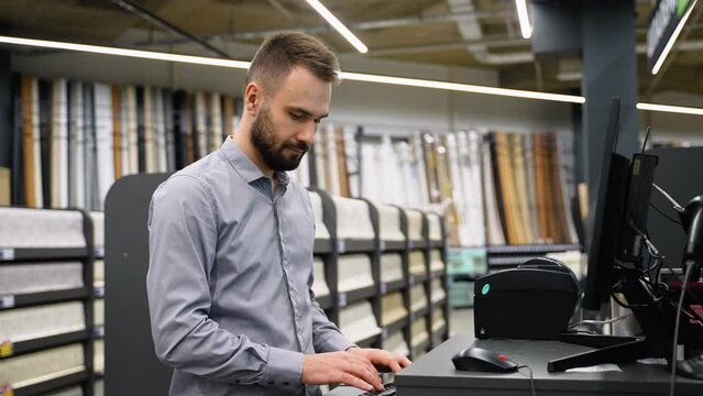Salesman in a wall covering store checking wallpaper on computer