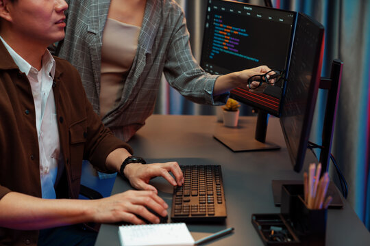 IT developers discussing with point to intelligent website development coder system running data online two screens information technology at neon light room at modern office. Infobahn.