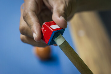 Close-up of male hand rubs the tip of a billiard cue with chalk for a more accurate shot 