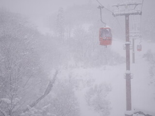 Ski lift cabin with people in the snowfall in mountains