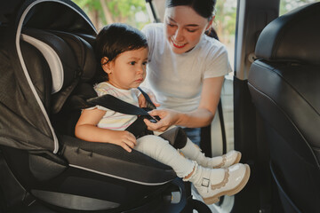 mother is fastening safety belt to unhappy toddler girl in car seat, safety baby chair travelling
