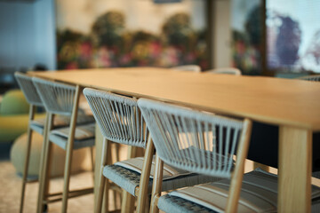 Woven chairs under a wooden table in a modern cafe