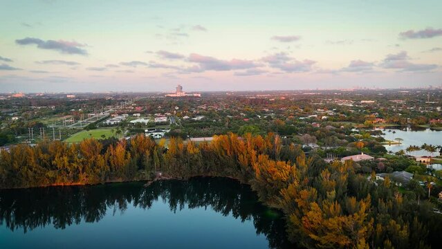 Aerial Pan of Wolf Lake Park in Davie, Florida, with Hard Rock Casino Guitar Hotel in the Background,  showcasing vibrant greenery, & a serene lake