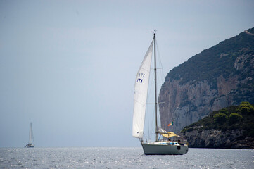 sailing boat on the sea, Sailboat sailing in the harbor of Porto Conte. In the background the Capo...