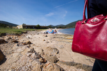 bag on the beach, Tourists in the bay of Tramariglio, Porto Conte Park, AMP Capo Caccia. Alghero....