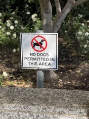 No dogs permitted in this area sign is displayed in a beautifully landscaped yard