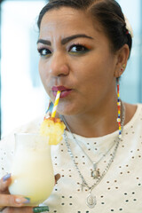Close up portrait of mexican woman smiling looking at camera holding pina colada in a restaurant
