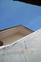 view of a house roof and walls with a view of the bright blue sky