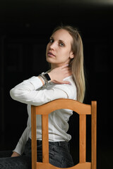 Portrait of a young beautiful blonde girl in a white shirt on a dark background.