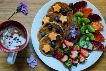 Chocolate raw cacao hot drink and banana pancakes made with roll oats, soy milk, banana  topping with fresh fruit and honey 
