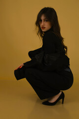 Portrait of a fashion model in the studio dressed in an elegant black jacket and trousers