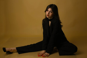 Portrait of a fashion model in the studio dressed in an elegant black jacket and trousers