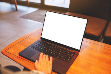 Mockup image of a woman using and touching on laptop computer with blank white desktop screen in cafe