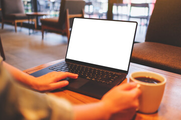 Mockup image of a woman working on laptop computer with blank white desktop screen while drinking coffee in cafe