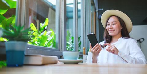 Portrait image of a beautiful young woman with hat holding and using mobile phone