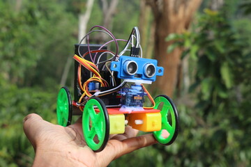 Holding a programmable robotic car that is capable of avoiding obstacles in is path and change the...