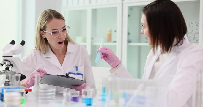 Chemist teaches assistant showing glass tube with liquid