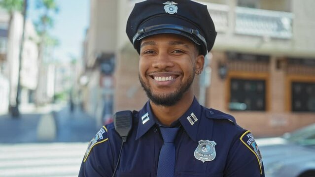 Smiling african american policeman wearing uniform in urban city environment